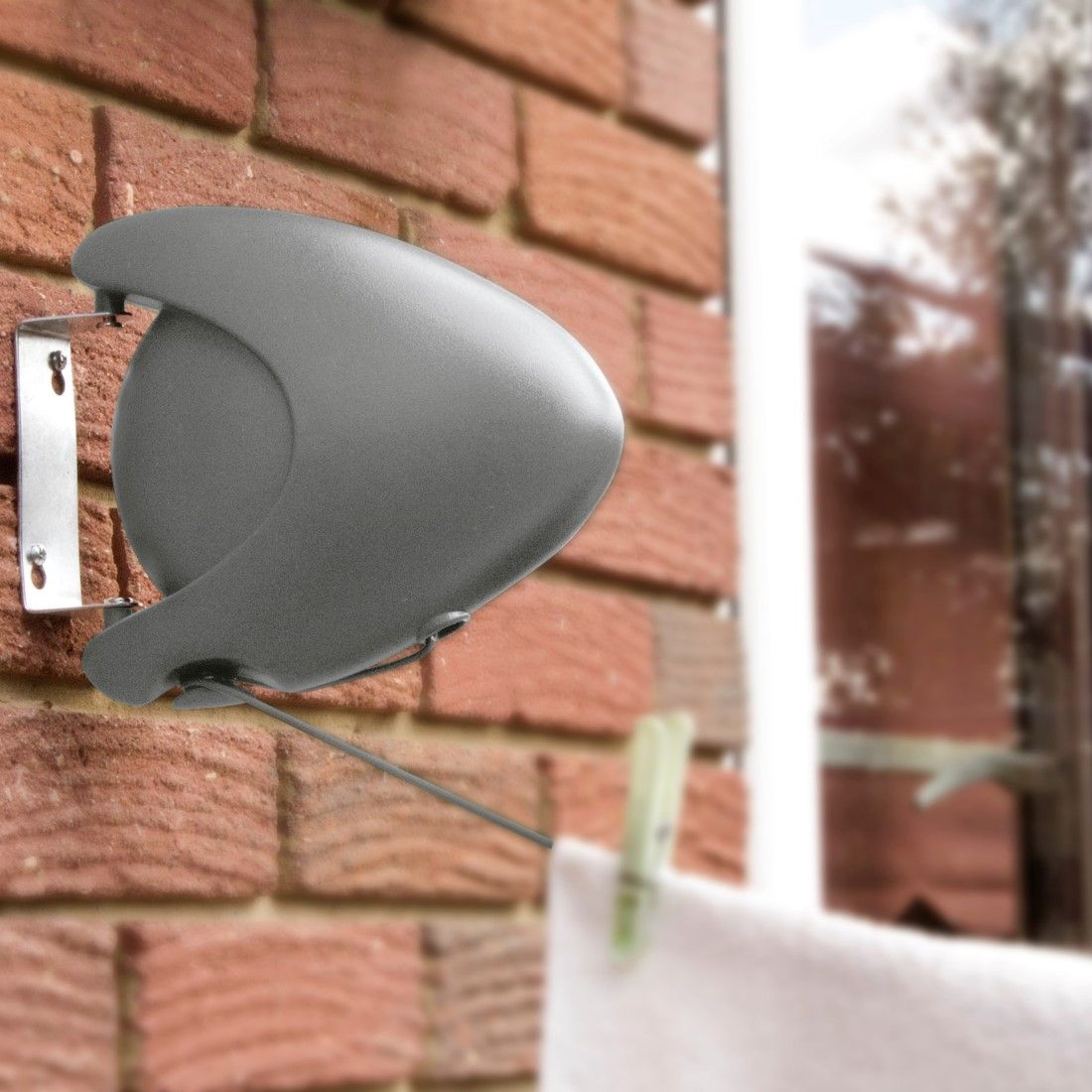 Outdoor Retractable Line attached to a wall with the washing line in use with a white towel pegged on to the line.