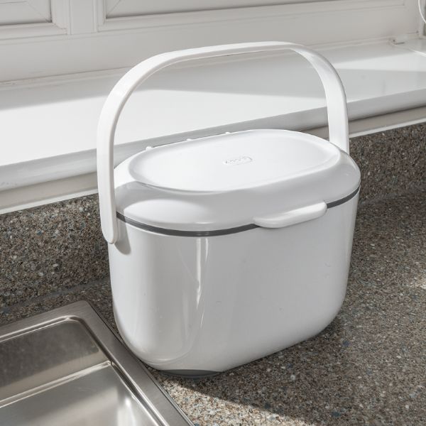 White compostable bin with handle on a kitchen counter.