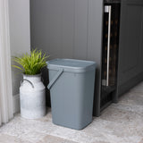 Small grey utility caddy next to a grey cupboard with a plant in a metal pot.
