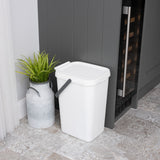 Small white utility caddy next to a grey cupboard with a plant in a metal pot.