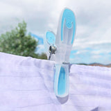 Clothes peg with blue accents on a white cloth on an outdoor clothes line.