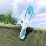Blue and clear clothes peg holding a green clothing item on the clothes line, with cloudy sky background