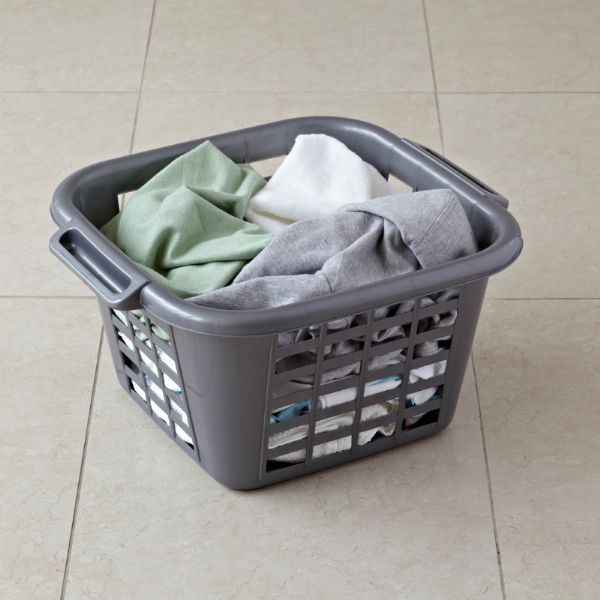 Grey laundry basket filled with clothes on a tiled floor