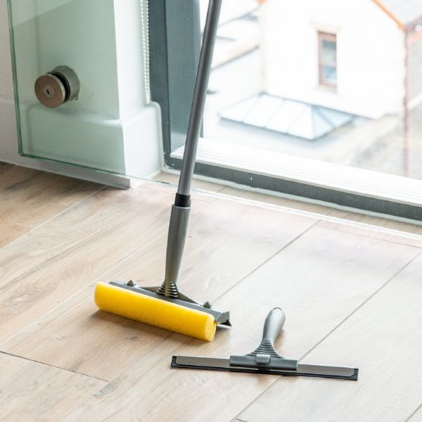 Cleaning tools on a wooden floor in front of a glass door.