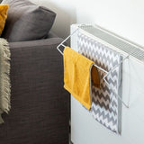 Radiator with towel rack holding yellow and patterned towels next to a sofa.