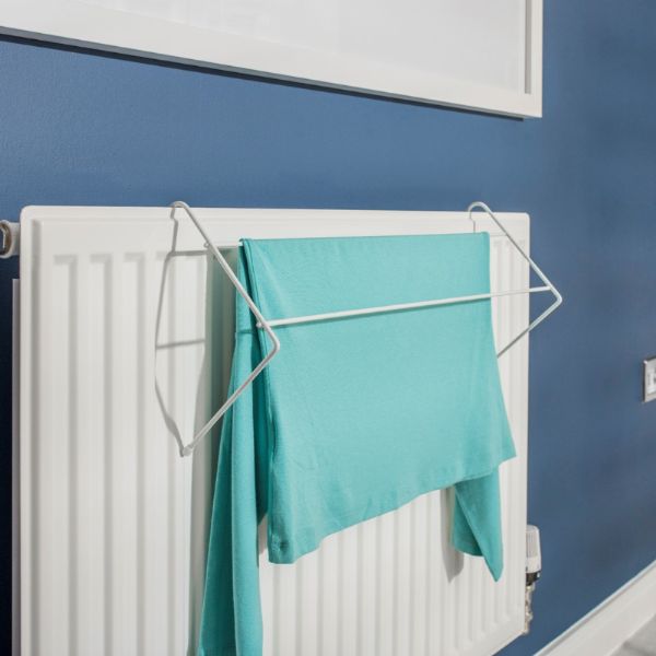 White radiator with a towel hanging on a rack against a blue wall.