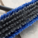 Close-up of a brush with blue and black bristles on a patio