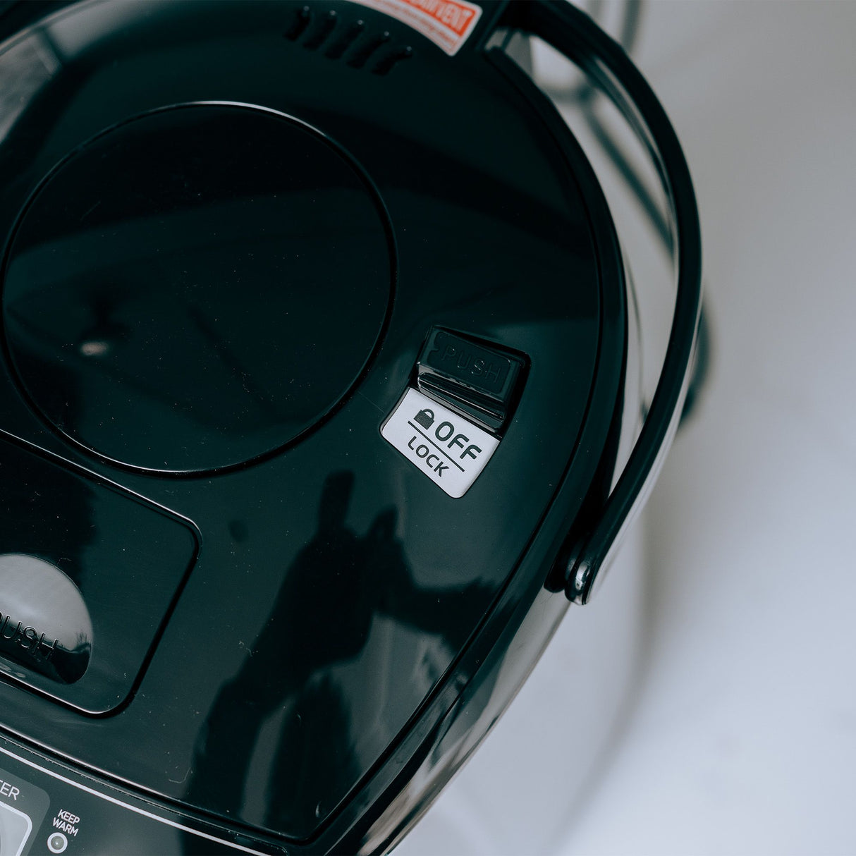 Close up of the lock catch on top of the thermo pot lid showing unlocked. 